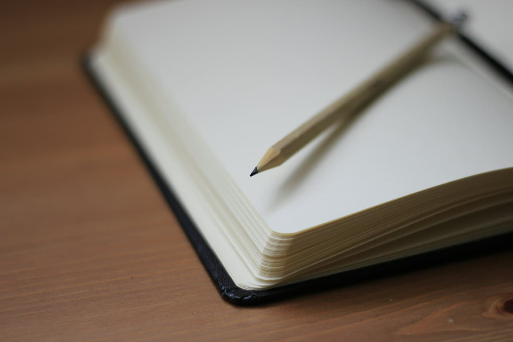 A pencil resting on the blank pages of an open notebook